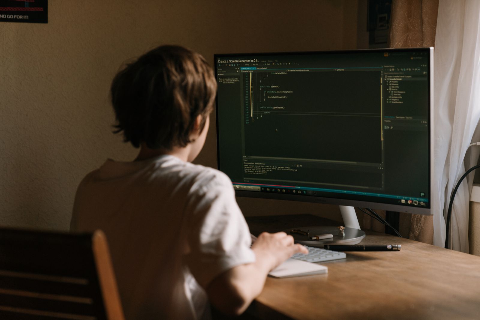 Un adolescente programa en una computadora de escritorio en su casa