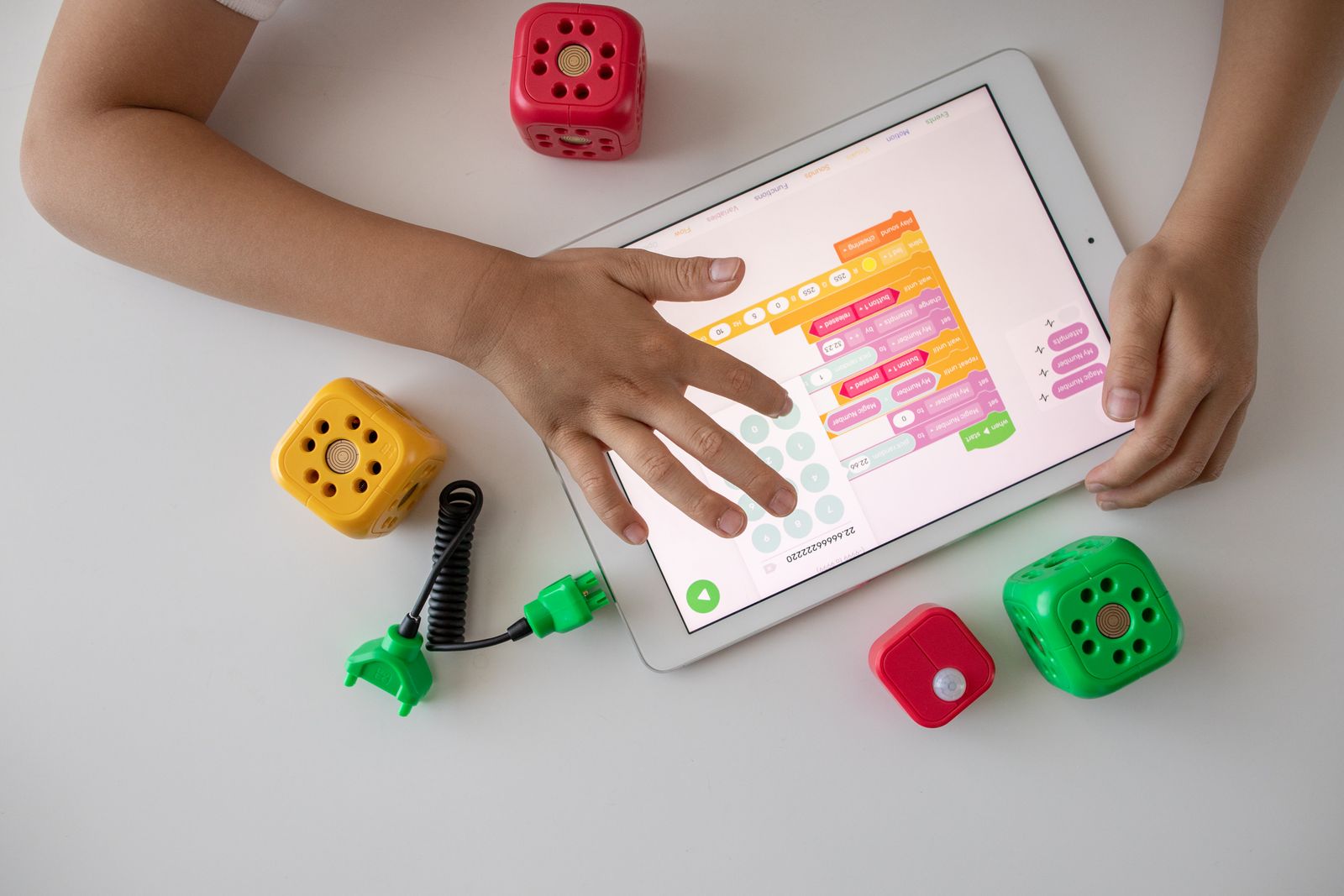 Manos de un niño programando con bloques de colores en una tablet